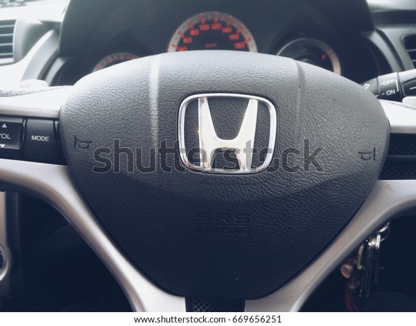 KUALA LUMPUR, January 13, 2016 : View of a hand\
holding HONDA steering and meter. Focus on HONDA logo. A crop close\
up steering wheels