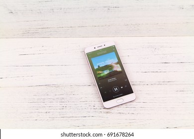 KUALA LUMPUR, MALAYSIA - 6th August 2017: A Smart Phone With Spotify Application On The Screen Over Wooden Texture Background. Spotify Is A Music, Podcast, And Video Streaming Service.