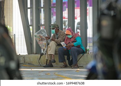 KUALA LUMPUR MALAYSIA - 9 April 2020:  Old Muslim Couple Reading Newspaper At Roadside Kuala Lumpur.