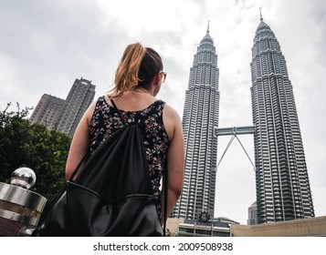 KUALA LUMPUR, MALAYSIA - APRIL 11, 2019: Young Traveller Girl Looking At The Iconic Petronas Towers From The Nearby KLCC Park In Kuala Lumpur City Centre, Kuala Lumpur, Malaysia.