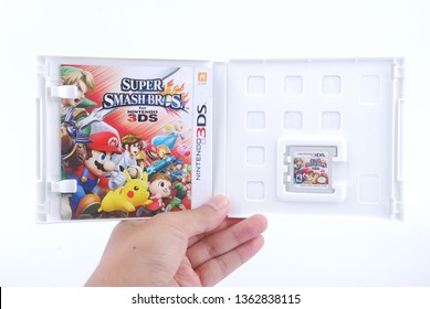 Kuala Lumpur, Malaysia - April 6, 2019: Man Holding Super Smash Bros Video Game On Nintendo 3DS Console On White Background.