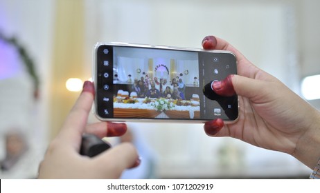Kuala Lumpur, Malaysia - April 8, 2018: Hands of woman taking photo with smartphone of Malay wedding ceremony. 