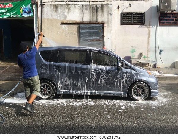 Kuala Lumpur, Malaysia - Augus 5, 2017: A worker\
at a car wash center is washing a local made car, Perodua Alza.\
Malaysia recently introduced E-card to crackdown illegal foreign\
workers.