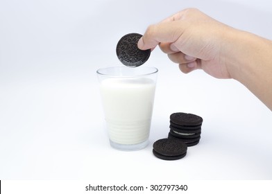 KUALA LUMPUR, MALAYSIA - AUGUST 3rd 2015. Hand Holding Oreo Cookies Dunk To Glass Of Milk. Oreo Is A Sandwich Cookie With A Sweet Cream Is The Best Selling Cookie In The US.