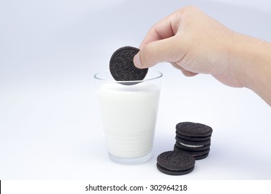 KUALA LUMPUR, MALAYSIA - AUGUST 3rd 2015. Hand holding Oreo Cookies dunk to glass of milk. Oreo is a sandwich cookie with a sweet cream is the best selling cookie in the US.