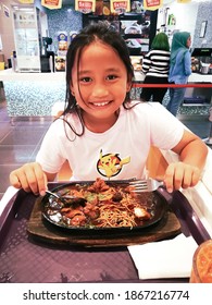 Kuala Lumpur, Malaysia - December 19, 2019:  Young Kid Girl Eating Sizzling Noodles At The Food Court.