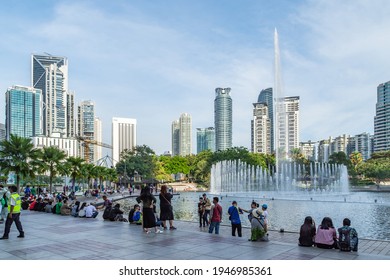 Kuala Lumpur, Malaysia - February 26th 2018: People Watching The Water Fountain Display On Lake Symphony In KLCC Park Which Is Overlooked By Skyscrapers.