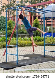 KUALA LUMPUR, MALAYSIA - JULY 26, 2020 : Asian Chinese Boy Kid Wear Mask Playing Monkey Bar At Playground 