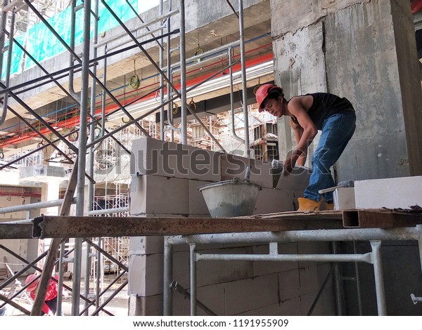 KUALA LUMPUR, MALAYSIA -JUNE 1, 2018: Bricklayer lay\
brick and stacked it together using cement mortar to built building\
wall at the construction site. Necessary tools required for this\
job. 
