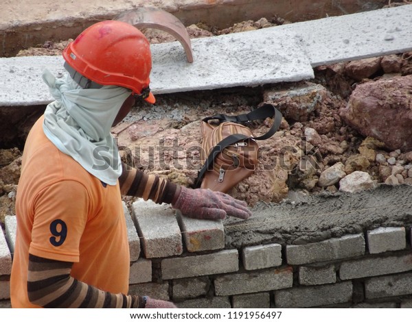KUALA LUMPUR, MALAYSIA -JUNE 1, 2018: Bricklayer lay\
sand brick and stacked it together using cement mortar to form\
monsoon drain wall at the construction site. Necessary tools\
required for this job. 
