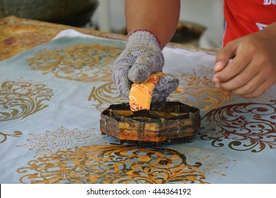KUALA LUMPUR, MALAYSIA -JUNE 25, 2016: An artist press get batik pattern using the mold or pattern block of batik tekap or stamp batik.  The block was made from metal & copper.