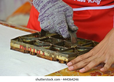 KUALA LUMPUR, MALAYSIA -JUNE 25, 2016: An artist press get batik pattern using the mold or pattern block of batik tekap or stamp batik.  The block was made from metal & copper.