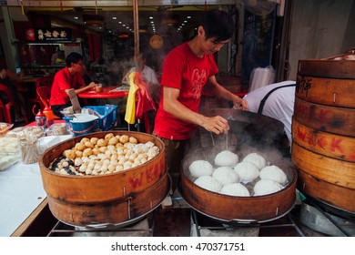 Kuala Lumpur, Malaysia - March 17, 2016:  Young man cooking chinese traditional steamed buns at the street food stall in Chinatown, Kuala Lumpur, Malaysia on March 17, 2016.
