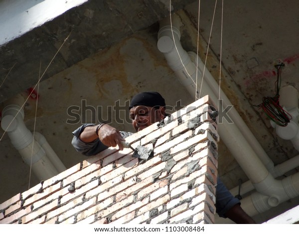  KUALA LUMPUR, MALAYSIA -MARCH 29, 2017: Bricklayer lay\
clay brick and stacked it together using cement mortar to form\
walls at the construction site. Necessary tools required for this\
job. 