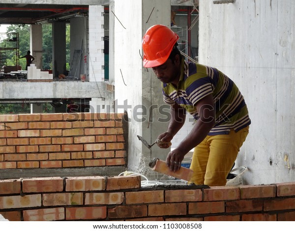  KUALA LUMPUR, MALAYSIA -MARCH 29, 2017: Bricklayer lay\
clay brick and stacked it together using cement mortar to form\
walls at the construction site. Necessary tools required for this\
job. 