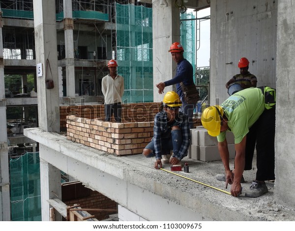 KUALA LUMPUR, MALAYSIA -MARCH 29, 2017: Bricklayer\
lay clay brick and stacked it together using cement mortar to form\
walls at the construction site. Necessary tools required for this\
job.