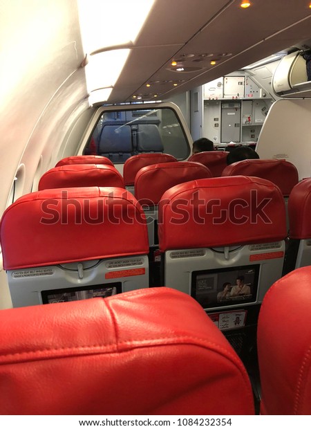 Kuala Lumpur, Malaysia - May 5, 2018 : The Air\
Asia economy flight seat red and grey with windows.Underexposure\
and blurry image.