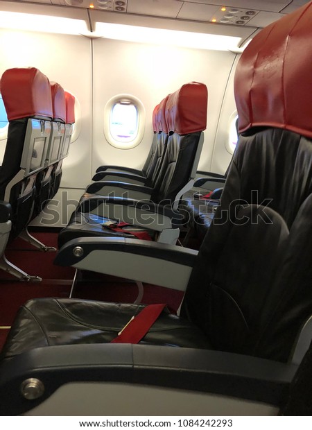 Kuala Lumpur, Malaysia - May 5, 2018 : The Air\
Asia economy flight seat red and grey with windows.Underexposure\
and blurry image.