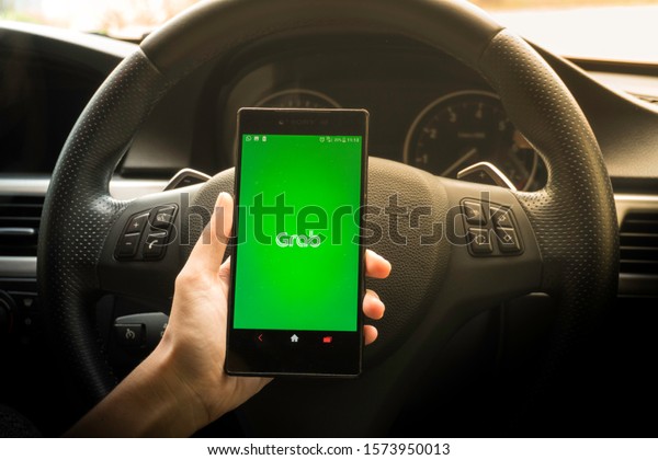 KUALA LUMPUR, MALAYSIA - NOV 29, 2019 : Stay\
connected and browsing Grab App with smartphone. Grab is smartphone\
app-based transportation network.\
