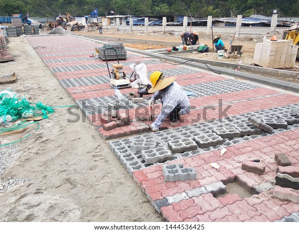 KUALA LUMPUR, MALAYSIA -NOVEMBER 15, 2017:\
Concrete pavers preparation and installation work by workers at the\
construction site car park area. It is arranged following the\
pattern and approved\
colour