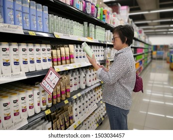 Kuala Lumpur Malaysia. Sept 8 2019. Woman Shopper Reading Label Of Shampoo Products At Supermarket Aisle By The Shelves. 