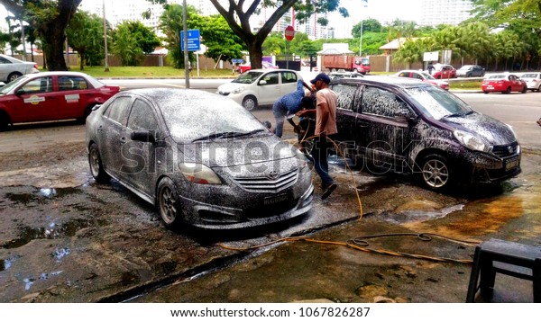 Kuala Lumpur, Malaysia-April 14th 2018:Foreign\
worker washing car on road\
side.