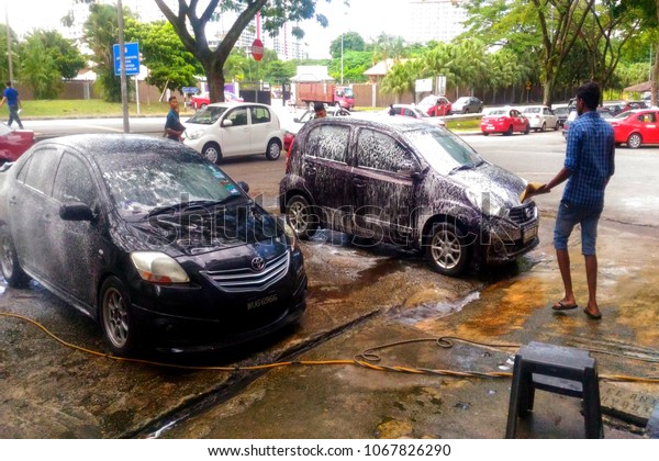 Kuala Lumpur, Malaysia-April 14th 2018:Foreign\
worker washing car on road\
side.