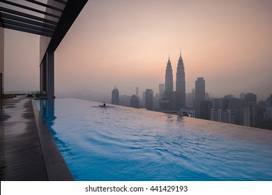 KUALA LUMPUR,MALAYSIA- JANUARY 13 2016:A man swims in infinity pool with the background of Kuala lumpur city. The buildings are soft due to the haze