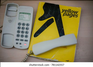 KUANTAN, MALAYSIA - December 23, 2017 : Yellow pages phone book with telephone isolated on desk - illustrative editorial.