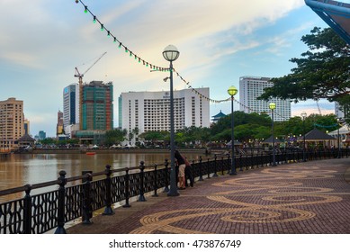 Kuching, Malaysia - Jan 04, 2016: Kuching City Waterfront At Sunset. People Walk On The Street. Sarawak. Borneo