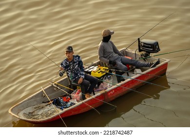 KUCHING, MALAYSIA - May 19, 2022: Two Fishermen On A Motorboat Fishing On The Sarawak River In Kuching, Malaysia