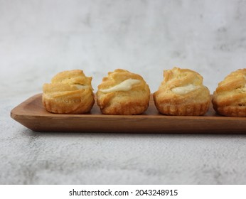 Kue Sus Durian Or Soes Vla Durian Or Cream Puff With Durian Custard Filling. On Wooden Plate. Selective Focus, Blurry Background, Bokeh Concept. 
