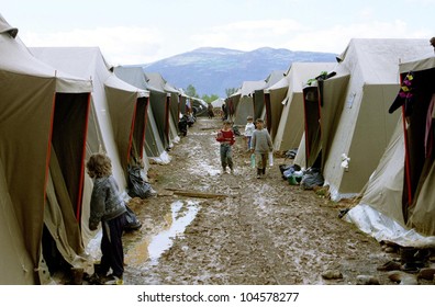 KUKES, ALBANIA, 19 APRIL 1999 -- A river of mud flows between rows of tents housing refugees at an Italian government-operated camp for Kosovar Albanians.