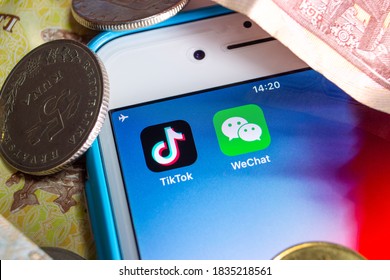 Kumamoto / JAPAN - Oct 2 2020 : TikTok & WeChat logos on iPhone with money (coins and banknotes) that randomly located.