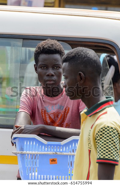 KUMASI, GHANA - JAN 15, 2017:\
Unidentified Ghanaian boys stand near the white car at the Kumasi\
market. Ghana people suffer of poverty due to the bad\
economy.