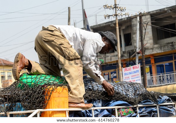 KUMASI, GHANA - JAN 15,\
2017: Unidentified Ghanaian man pulls on a net on the top of the\
car at the Kumasi market. Ghana people suffer of poverty due to the\
bad economy.
