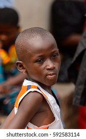 KUMASI, GHANA - Jan 16, 2017: Unidentified Ghanaian little girl with short haircut sits in the crowd. People of Ghana suffer of poverty due to the bad economy