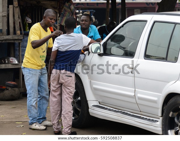 KUMASI, GHANA - Jan 16, 2017: Unidentified\
Ghanaian boys stand near the white car. People of Ghana suffer of\
poverty due to the bad\
economy