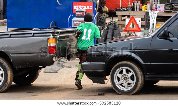 KUMASI, GHANA - Jan 16, 2017: Unidentified\
Ghanaian boy runs between two cars. Children of Ghana suffer of\
poverty due to the bad\
economy