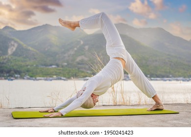 Kundalini Yoga Woman In White Clothes And Turban Practices Yoga Kundalini On The Background Of The Sea, Mountains And Sunset. Fighting Face Painting Of The Indians Shows Her Inner World. Visual