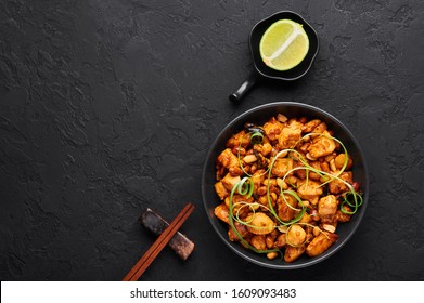 Kung Pao Chicken or Gong Bao Ji Ding at dark slate background. Sichuan Kung Pao is chinese cuisine dish with chicken meat, chilli peppers, peanuts, sauces and onion. Copy space. Top view