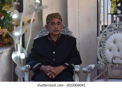 Kuningan, West Java, Indonesia - August 8th 2021: A Middle-aged Man Wearing Sundanese Traditional Clothes And Blankon Is Sitting. Close Up. Front View.