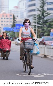 KUNMING, CHINA-JUNE 30, 2014. Cyclist With Breath Protection. Despite Marginal Improvements In Worst Areas, Nearly 300 Chinese Cities Failed To Meet National Air Quality Standards In 2015, Greenpeace Said. 