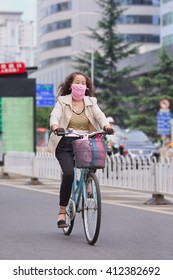 KUNMING, CHINA-JUNE 30, 2014. Woman Cycles With Mouth Cloth. Despite Some Improvements In Worst Areas, Nearly 300 Chinese Cities Failed To Meet National Air Quality Standards In 2015, Greenpeace Said.