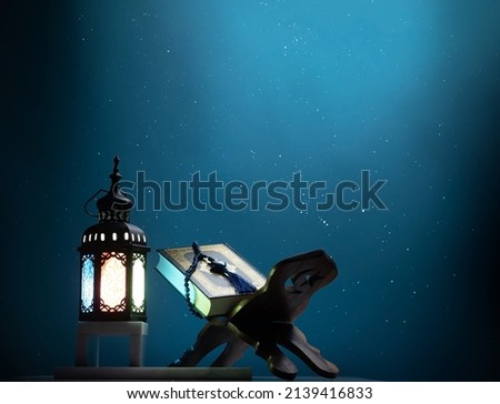 Kuran or Quran , the holy book of all Muslim shined by brighten lantern on dark blue background