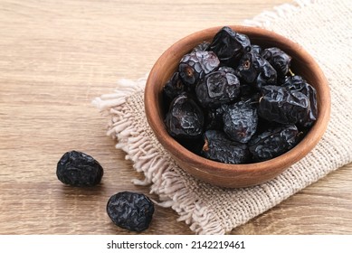 Kurma Ajwa, Ajwa Dates, served in small plate. Kurma Ajwa is one of the special fruit of Arabic. Served in wooden bowl on wooden background.
