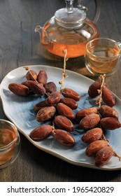 Kurma Dried Dates Fruit On Oval Plate Above Brown Wooden Table, Serve With Tea On Brown Table Background 