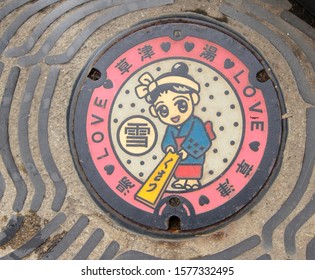 Kusatsu, Japan - November 22, 2019 - Manhole with the Kusatsu mascot: A girl doing "Yumomi", a traditional technique to cool down hot spring water.