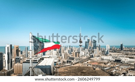 Kuwait flag waving in the wind over the Kuwait City cityscape.