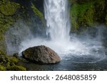 Kvernufoss Water tumbles from a towering cliff into a serene pool surrounded by vibrant moss-covered rocks. This natural wonder captures the essence of Iceland stunning geology and beauty.